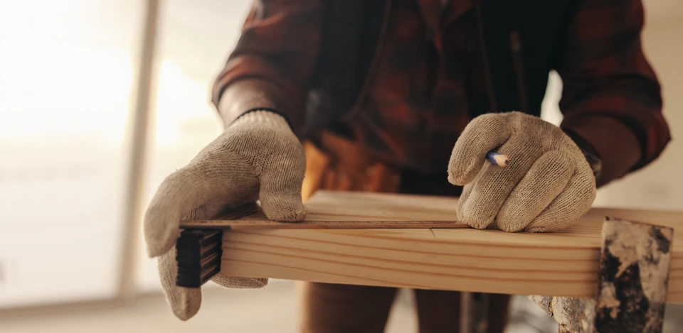 Le propriétaire mesure et marque le bois pour la rénovation d'un intérieur de maison