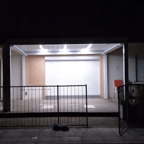 Garage résidentiel nocturne avec portail métallique ouvert, éclairage LED intégré au plafond