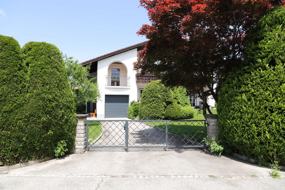 Façade extérieure de maison individuelle moderne avec portail métallique à mailles losangées et piliers en pierre
