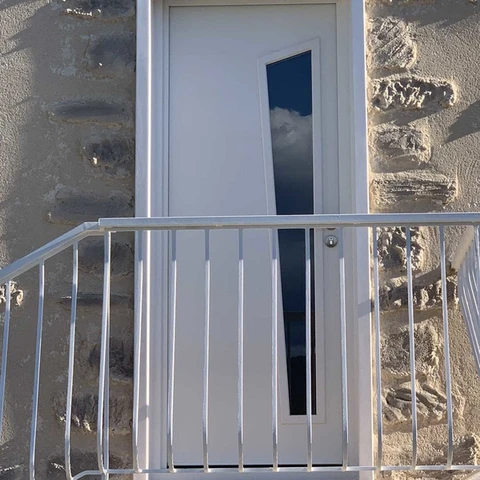 Façade extérieure d'immeuble avec porte d'entrée blanche moderne équipée d'un panneau vitré vertical