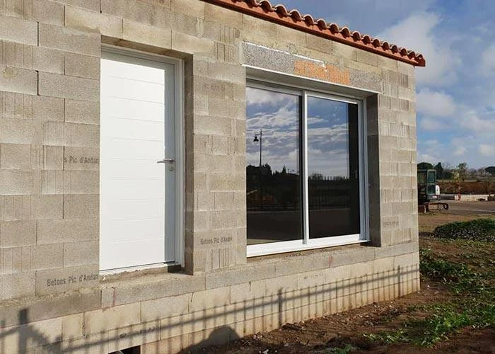 Extérieur d'un bâtiment en bois avec grande baie vitrée à cadre métallique bleu-gris