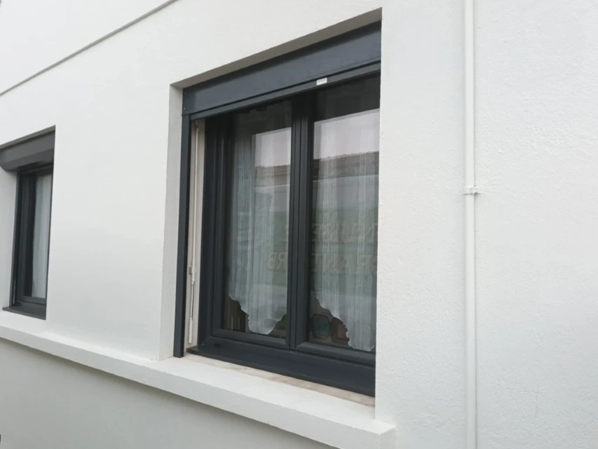 Véranda moderne avec structure aluminium noir, grandes baies vitrées panoramiques et toiture transparente