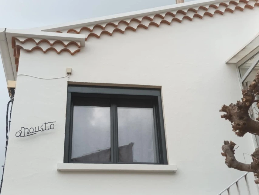 Extérieur d'un bâtiment en bois avec grande baie vitrée à cadre métallique bleu-gris