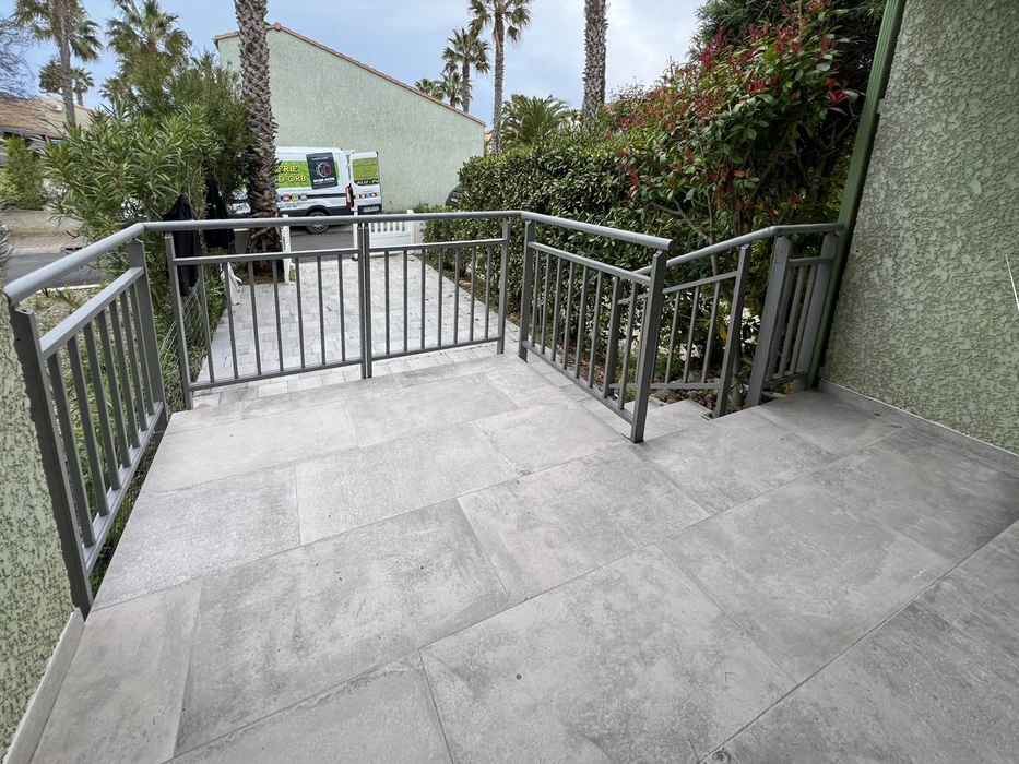 Façade de maison résidentielle avec entrée principale protégée par un auvent moderne à structure métallique blanche