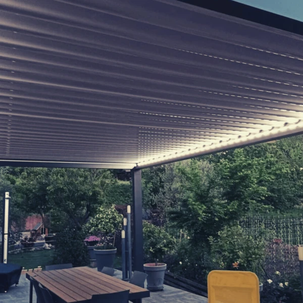 Deux ouvriers installent une pergola en aluminium à lames orientables sur une terrasse extérieure