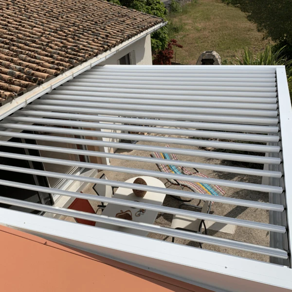 Trois ouvriers en uniformes noirs travaillent sous une pergola bioclimatique avec lames orientables