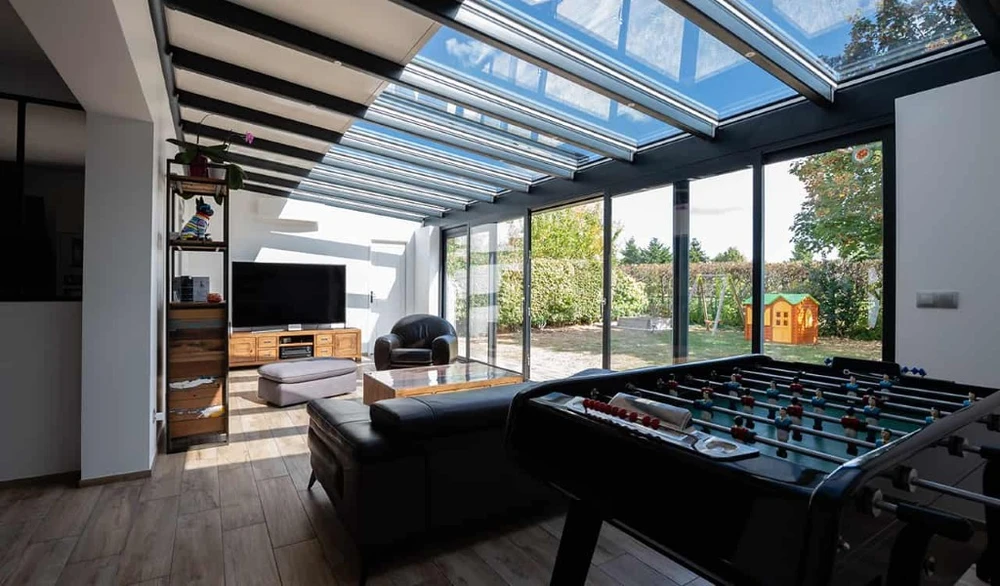 Trois ouvriers en uniformes noirs travaillent sous une pergola bioclimatique avec lames orientables