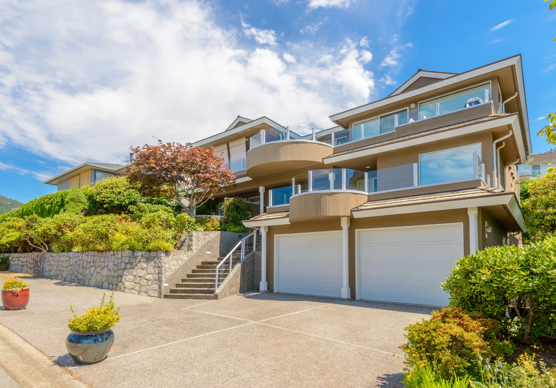 Façade résidentielle moderne avec garage intégré, entrée principale surélevée par escalier en béton